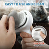 A hand is using a white pet grooming steam brush on a cat, demonstrating the one-click clean button feature.