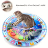 Un chaton tabby sur un tapis sensoriel bleu avec poissons et jouets colorés, à côté d'une tondeuse à ongles.
