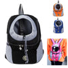 An orange and gray portable pet carrier backpack with a black interior and a small black dog visible.