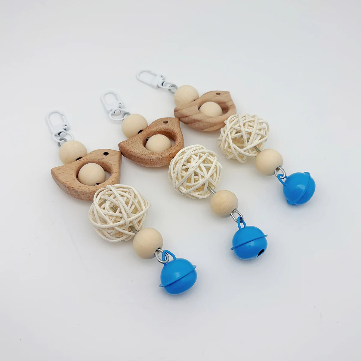 A set of decorative parrot swing toys featuring wooden birds and spherical balls suspended by silver chains.
