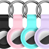 A silicone protective cover for an AirTag attached to a keychain, shown in black, pink, cyan, and purple colors.