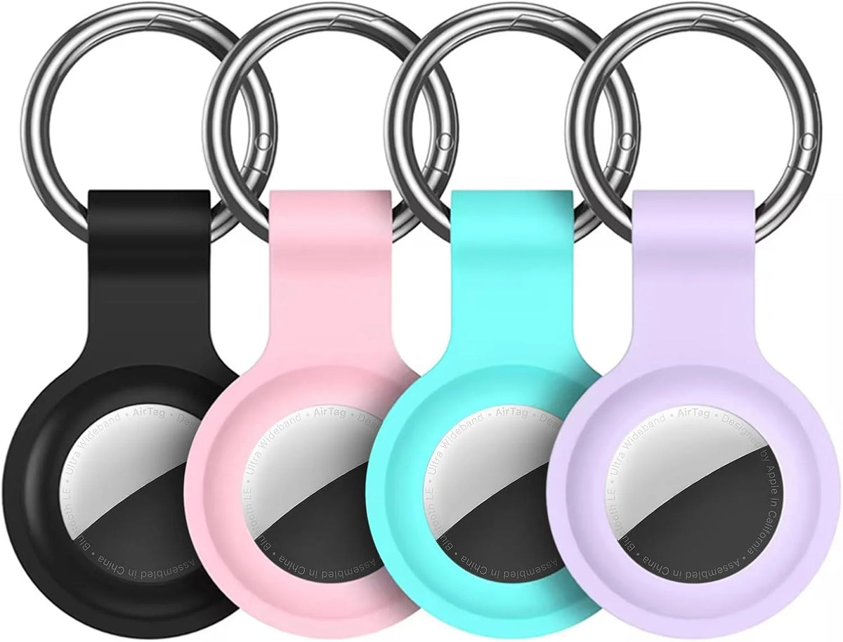 A silicone protective cover for an AirTag attached to a keychain, shown in black, pink, cyan, and purple colors.