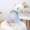 A fluffy white dog wearing a pink princess style denim jacket with a crown and bow.