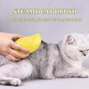 A hand is using a yellow steamy cat brush to massage and clean floating hair on a gray and white cat.