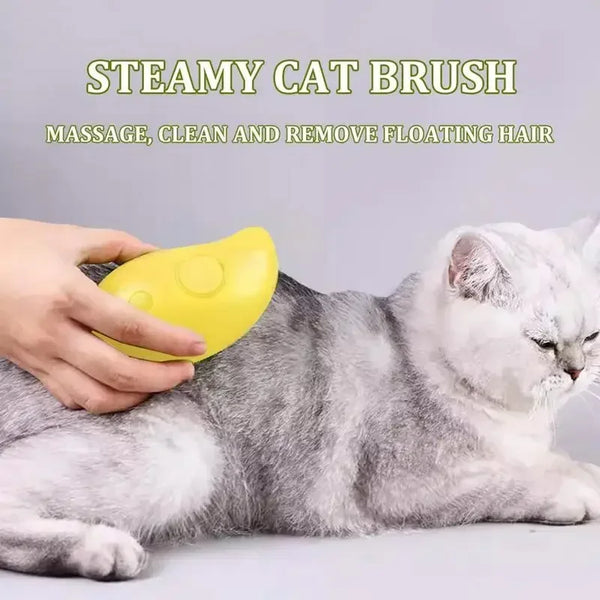 A hand is using a yellow steamy cat brush to massage and clean floating hair on a gray and white cat.