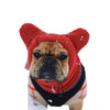 A close-up of a red fleece dog winter hat with orange-brown fur texture and black trim.
