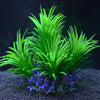 Un amas de plantes aquatiques artificielles vert vif avec des fleurs violettes dans l'eau sombre.
