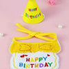 Un ensemble de bibs et chapeaux de fête jaunes avec un pompon jaune et du texte brodé sur un fond rose.