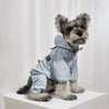A gray dog wearing a light blue waterproof raincoat and jumpsuit.