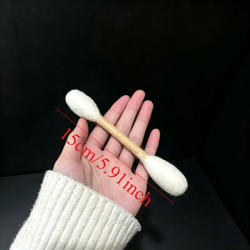A hand holds a white cotton swab with catnip attached, measuring 15cm or 5.91 inches.