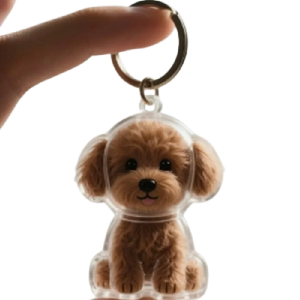 Un pequeño y peludo charm de perro marrón unido a un anillo de llavero de plata.