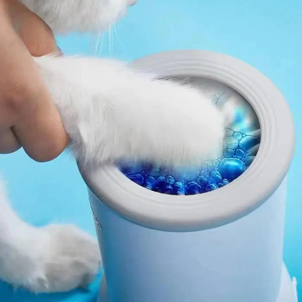 A hand is cleaning a white pet paw inside a white cup, which is part of an automatic pet paw cleaner system.