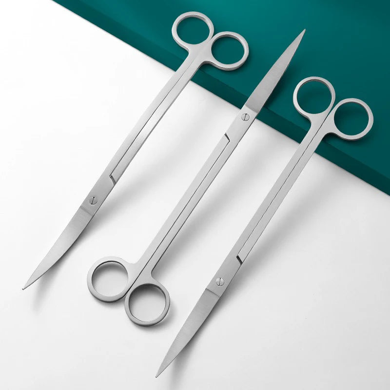 Set Edelstahl-Aquarium-Reinigungswerkzeuge mit Schere und Messer auf blaugrüner Oberfläche.