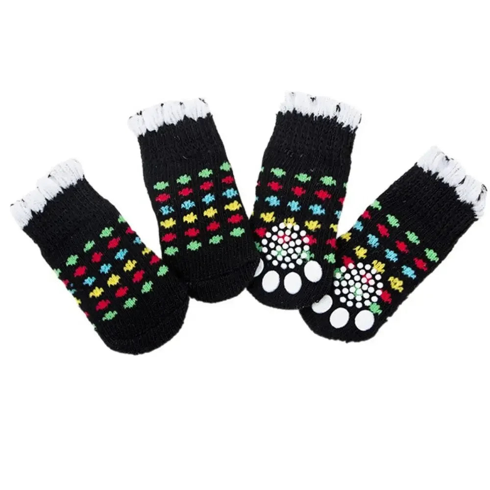 A pack of four black anti-slip pet socks with colorful patterns for dog and cat protection