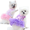 Un perro blanco vistiendo un vestido de encaje de gasa rosa con capas de volantes morados.
