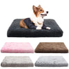 A fluffy brown and white dog is resting on a dark gray orthopedic rectangular dog bed with various colored removable covers.