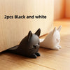 Two black and white cat-shaped door stoppers placed on a wooden surface.