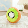 A plush toy shaped like an avocado with a kiwi pattern on the skin, resting on a white lace surface.
