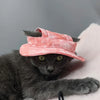 Un gato gris vistiendo un sombrero para los oídos rosa ajustable.