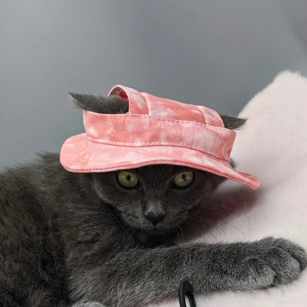 Un gato gris vistiendo un sombrero para los oídos rosa ajustable.