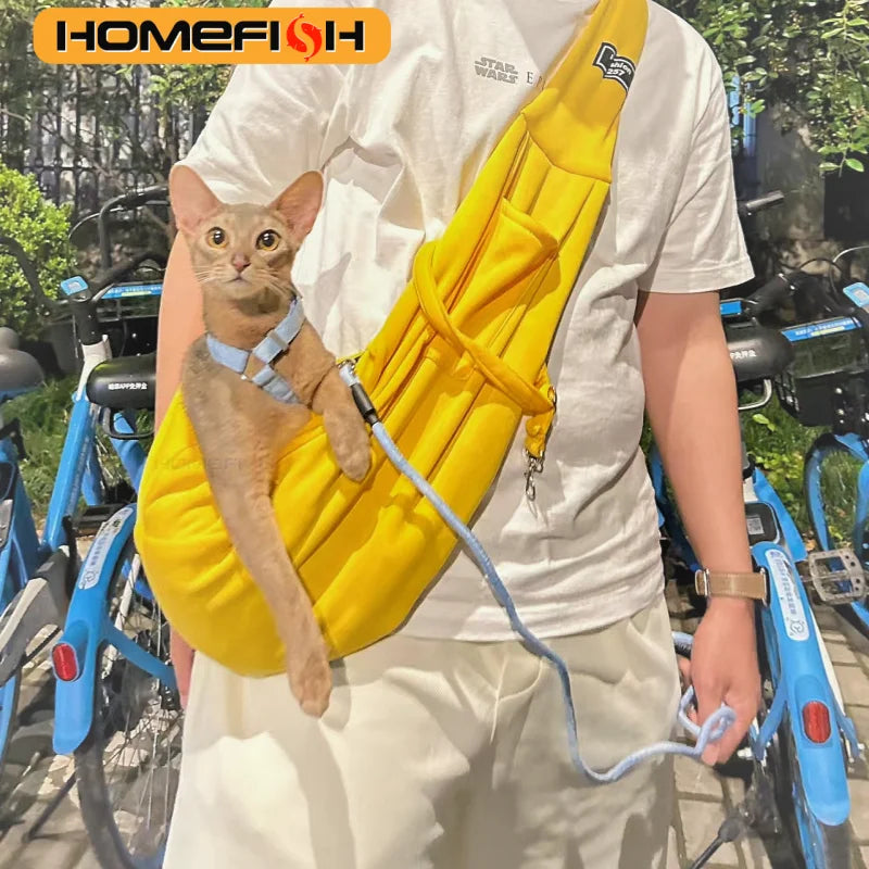 A person is holding a yellow adjustable crossbody dog sling carrier with a small cat in the sling.