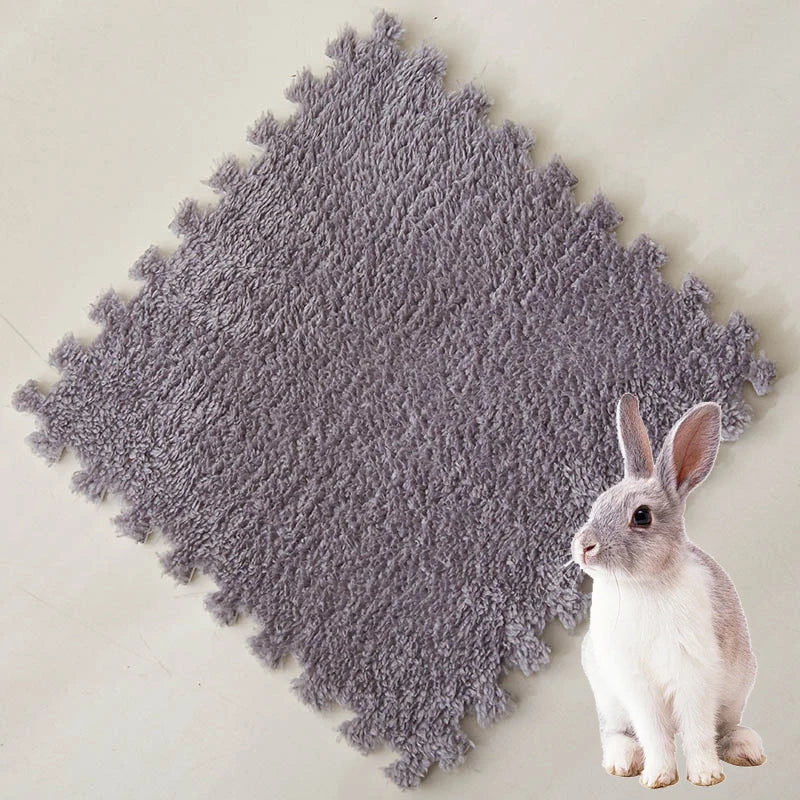 A small gray rabbit sitting on a textured gray fleece pet warming mat.