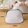 Una bolsa de lavandería de malla reutilizable blanca sobre un suelo de madera junto a una persona poniéndose un zapato blanco