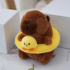 A brown capybara plush toy with a yellow hoodie and a small yellow chick attached, resting on a white box.