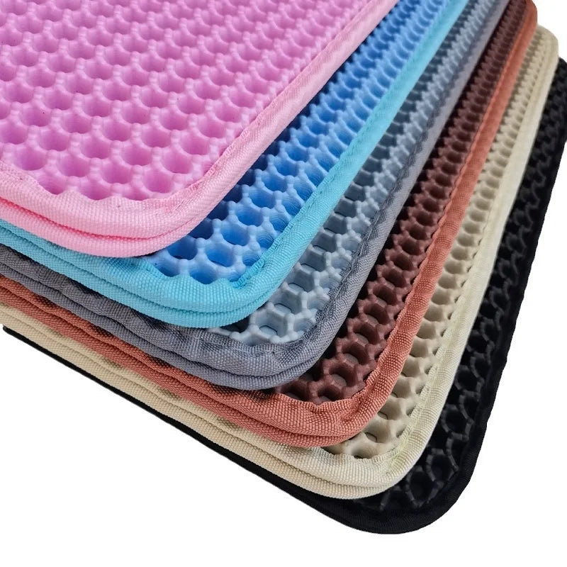 Pile de tapis pour litière imperméables colorés pour boîtes de chat aux tons rose, bleu, gris et marron.