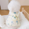 Vestido de malla blanca para perro con collar pompón blanco esponjoso y detalles florales azules.
