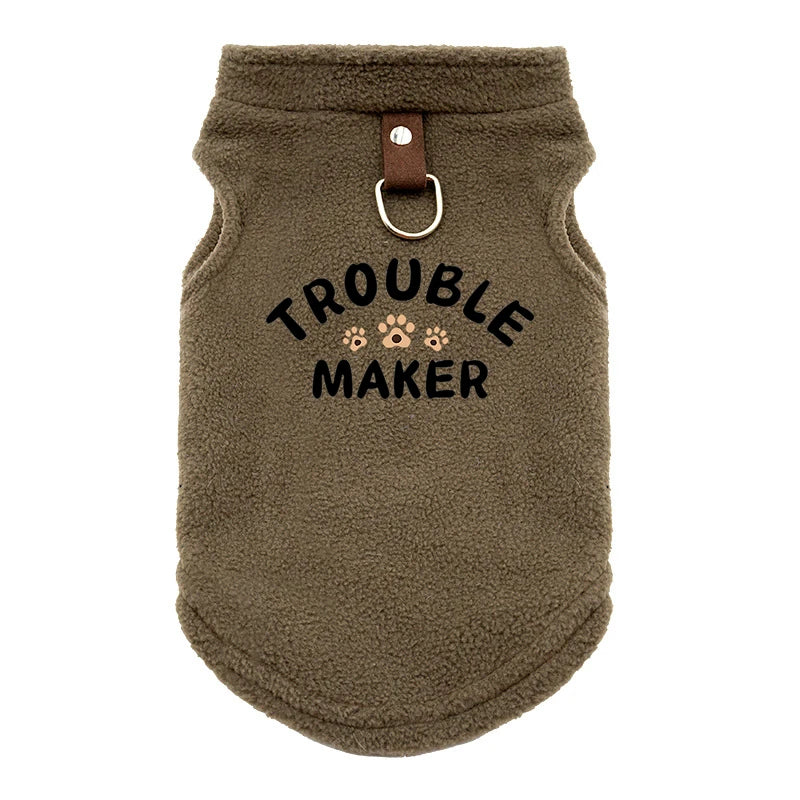 A brown, fuzzy pet jacket for dogs with a leather-look collar and embroidered text that reads Trouble Maker.