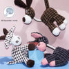 A plush squeaker toy of a donkey dog with black and white fur is shown in various poses.