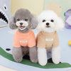 Dos perros pequeños vistiendo abrigadores de invierno de peluche, uno gris y otro blanco, sentados sobre una superficie azul 