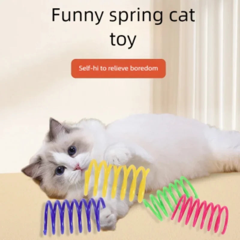 Eine weiße und graue Katze spielt mit einem gelb-grünen spiralförmigen Spielzeug.