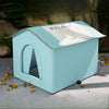 A light blue, foldable pet bed with a pitched roof and an arched entrance is shown on a gray surface.