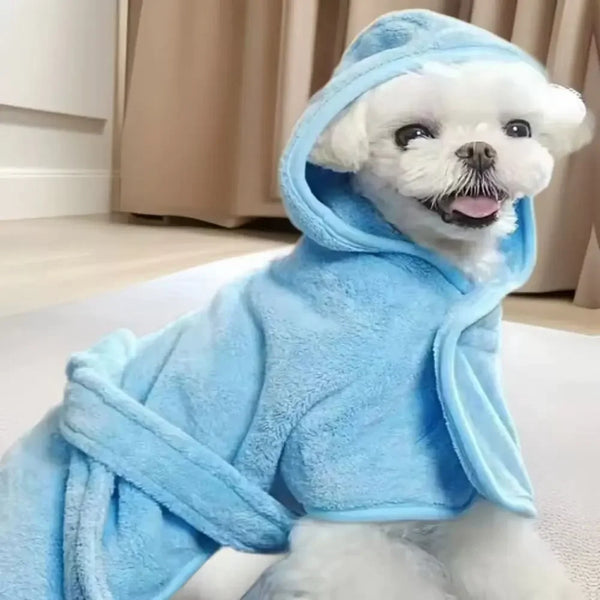 A white dog wearing a light blue fuzzy pet bath robe with a hood.