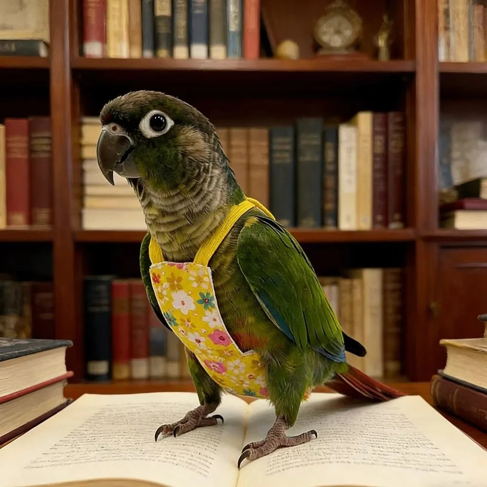 A green parrot wearing a yellow patterned flight suit standing on an open book in a wooden bookshelf setting.