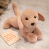 A soft, light tan plush dog toy resembling a puppy is lying on a white textured surface.