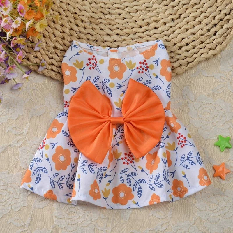 Robe d'été orange et blanc à motifs floraux avec un grand nœud orange, présentée sur un tapis tissé.