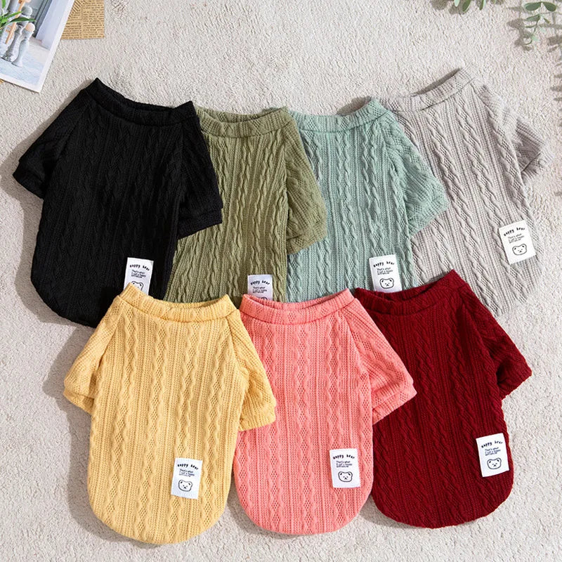 A collection of knitted winter sweaters for dogs and cats in various shades of green, pink, and red.