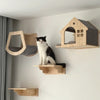 A black and white cat sits on a wooden modular wall shelf featuring a bridge and a house-shaped perch.