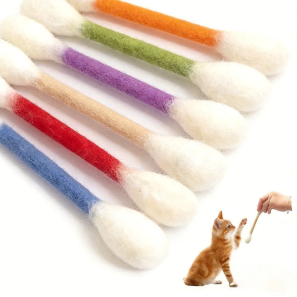 Eine Sammlung farbenfroher, flauschiger Katzenkaugummis mit natürlichem Katzenminze neben einem kleinen orangefarbenen Kätzch