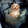 A golden-colored dog is sitting inside a green pet car kennel in a dark car interior.
