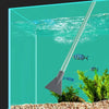 A long, silver aquarium gravel cleaner and water changer with a siphon pump is shown dipping into clear water above decorativ