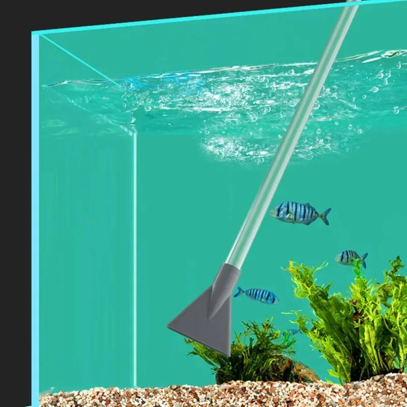 A long, silver aquarium gravel cleaner and water changer with a siphon pump is shown dipping into clear water above decorativ