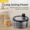 A black stainless steel pet water fountain with a visible water flow and sensor is shown next to a cat.