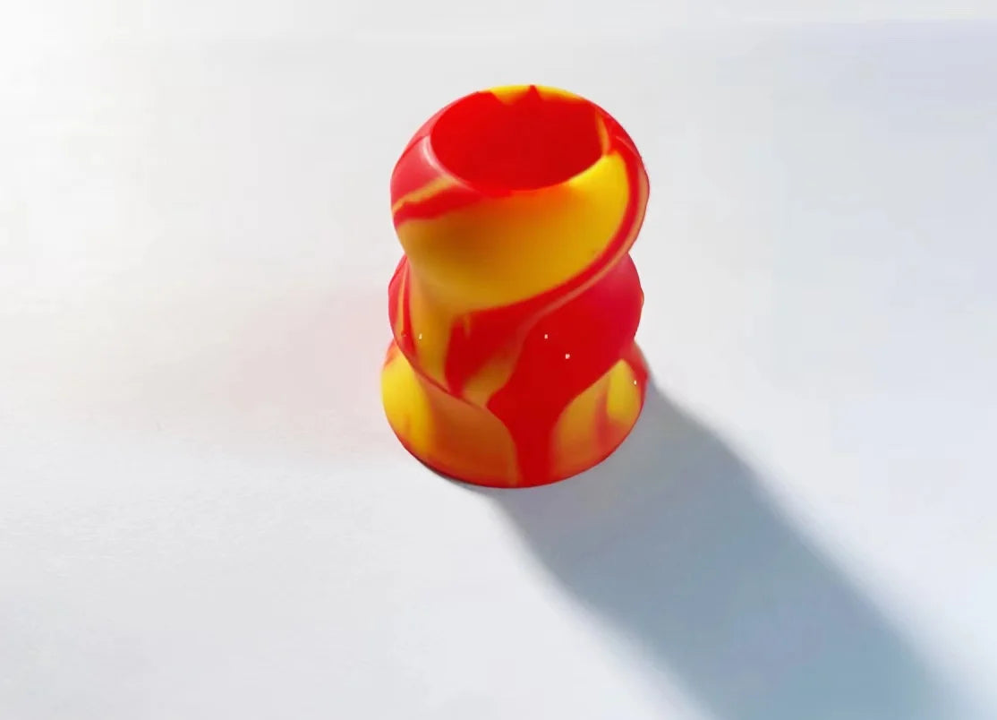 A stack of silicone bat grip knobs in red and yellow swirling patterns.