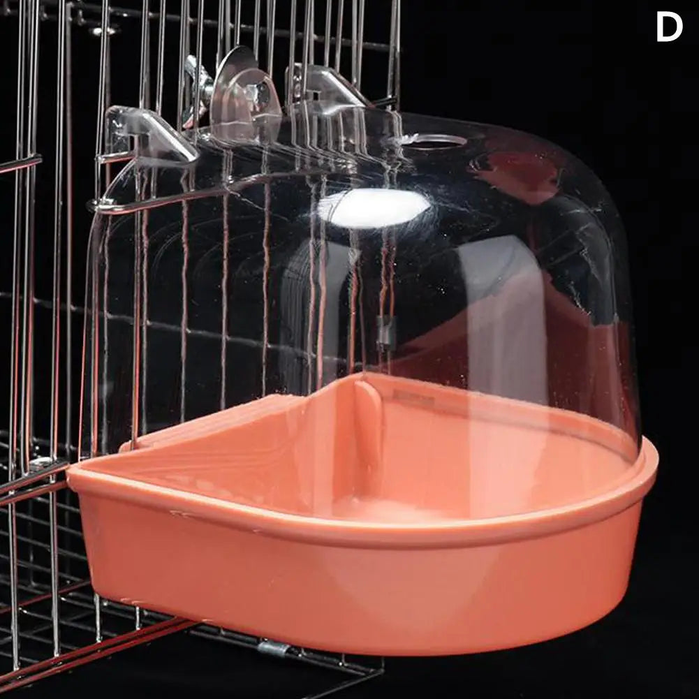 A clear plastic hanging bird bath for parakeets is shown in a wire cage.