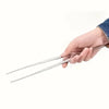 A hand holds a pair of precision stainless steel tweezers with straight and curved tips.