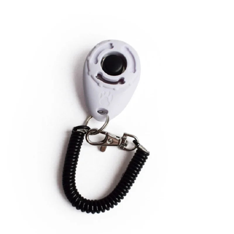 Weißes Hundetrainer-Klickergerät an einem schwarzen Armband.